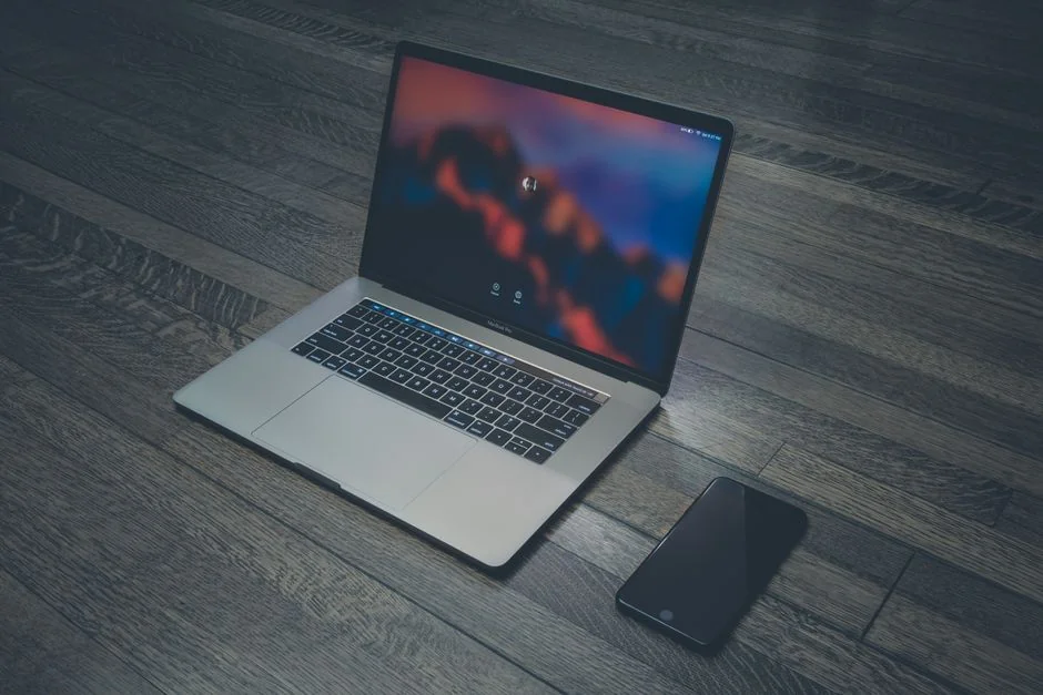 Close-up of a laptop and tablet on a wooden desk, showcasing modern technology.